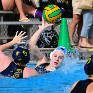 A water polo player extends their arm to block an incoming ball