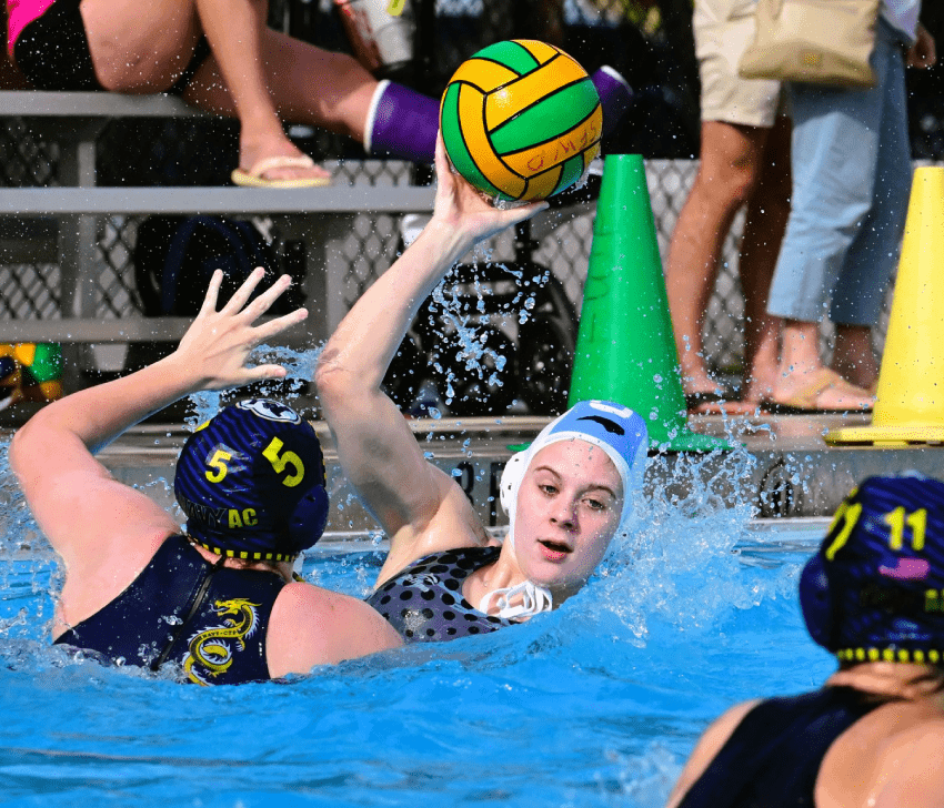 A water polo player extends their arm to block an incoming ball